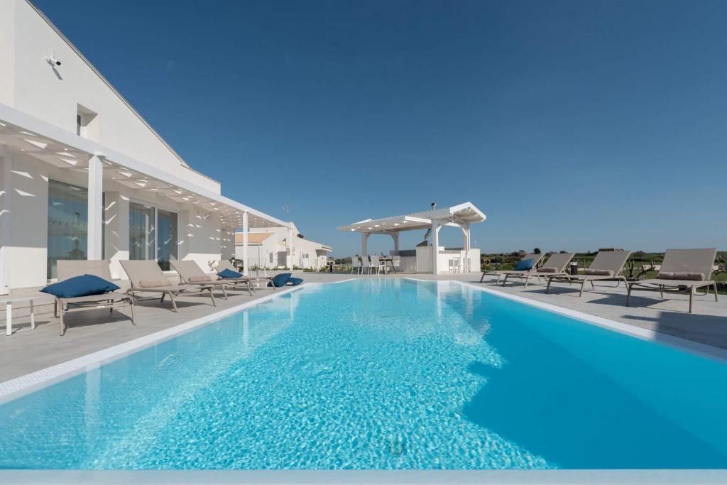 une piscine avec des chaises longues à côté d'un bâtiment dans l'établissement Villa White - IsulaTravel, à Modica