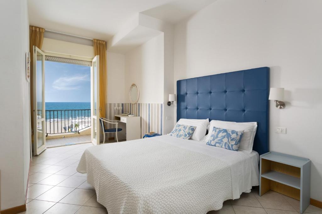 une chambre avec un grand lit et une vue sur l'océan dans l'établissement Ambasciatori Hotel - Beach Front -Breakfast XXL & Brunch until 12 30pm, à Misano Adriatico