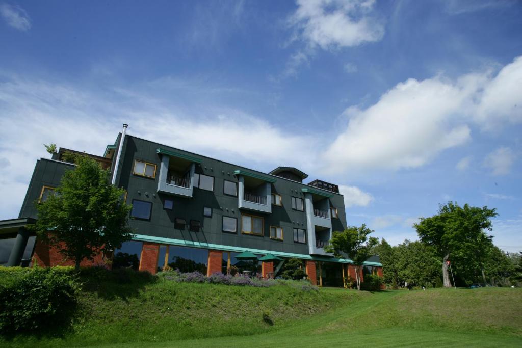 un grand bâtiment au sommet d'une colline herbeuse dans l'établissement Sanyoan, à Otofuke
