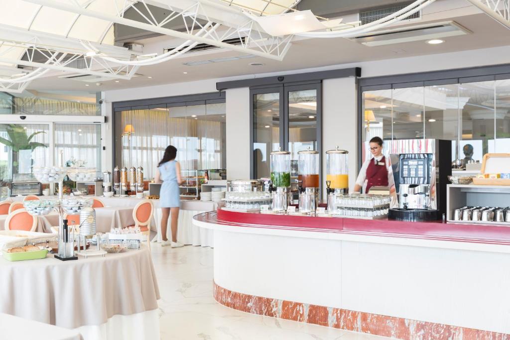 un restaurant avec 2 personnes debout à un comptoir dans l'établissement Hotel Cambridge, à Lido di Jesolo