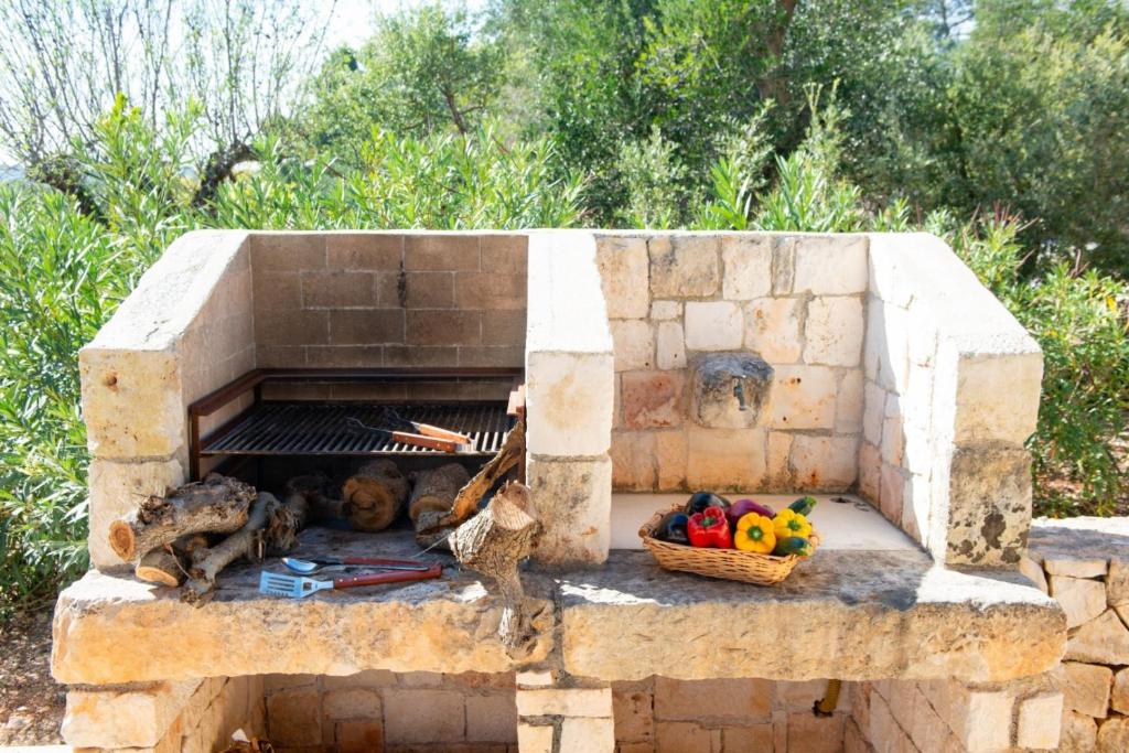 - un four en briques avec des poulets et un panier de légumes dans l'établissement HelloApulia Trulli Andel, à Ostuni