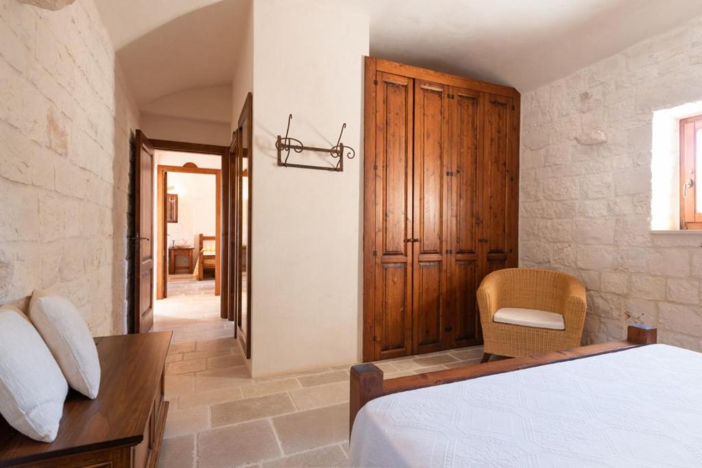une chambre avec un lit et une armoire en bois dans l'établissement HelloApulia Trulli Andel, à Ostuni 33 autres photos