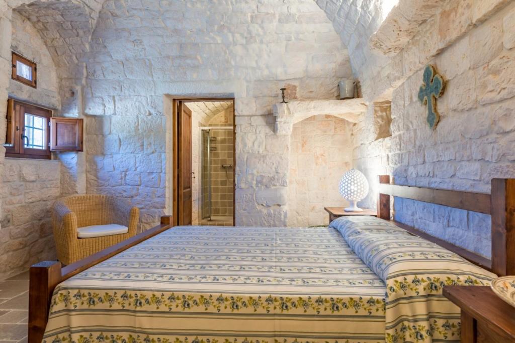 une chambre avec un lit dans un mur de pierre dans l'établissement HelloApulia Trulli Andel, à Ostuni