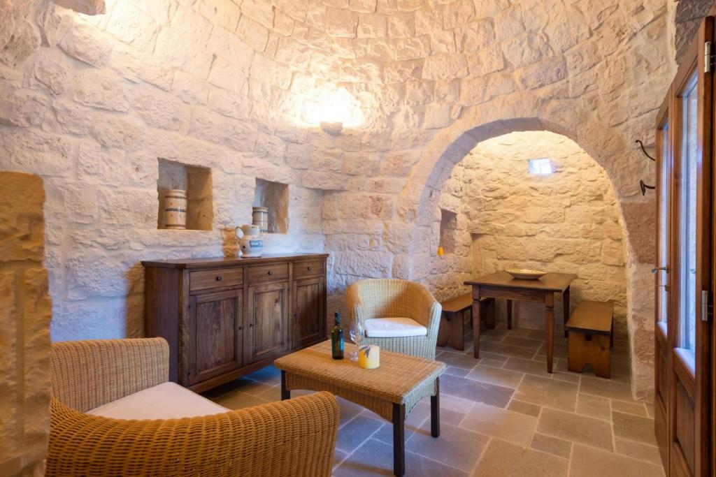 Cette chambre est dotée d'un mur en pierre avec une table et des chaises. dans l'établissement HelloApulia Trulli Andel, à Ostuni