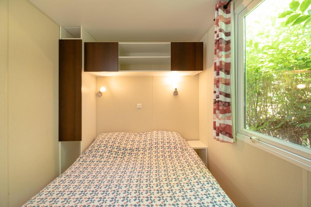 une petite chambre avec un lit et une fenêtre dans l'établissement Camping Le Parc des Monges, à Auribeau-sur-Siagne 37 autres photos
