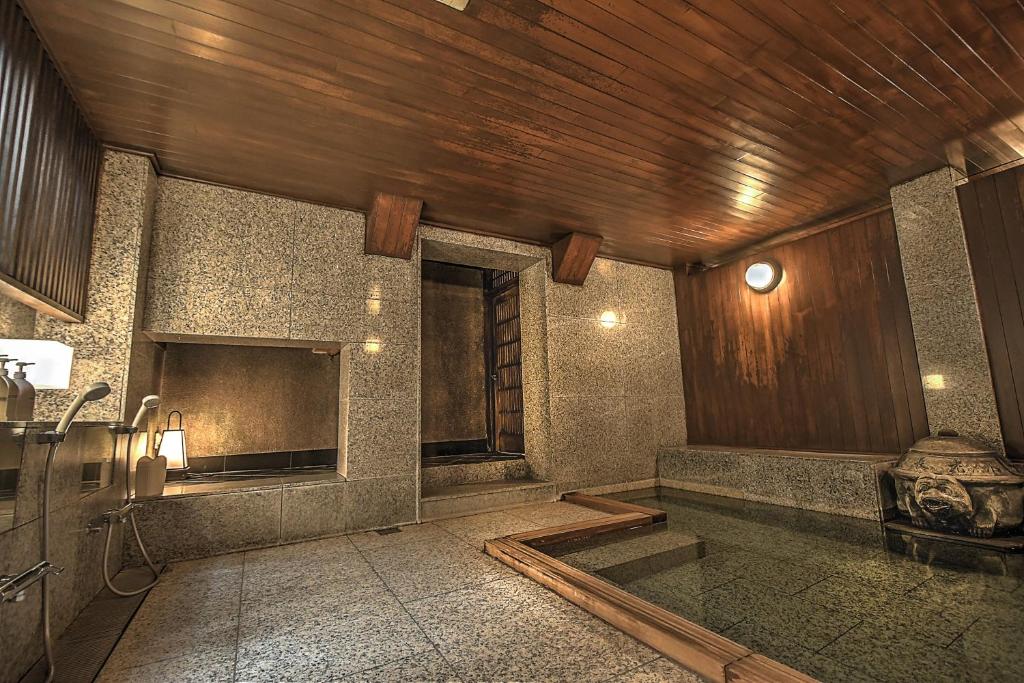 La salle de bains est pourvue d'une baignoire et d'un plafond en bois. dans l'établissement K's House Ito Onsen - Historical Ryokan Hostel, à Itō