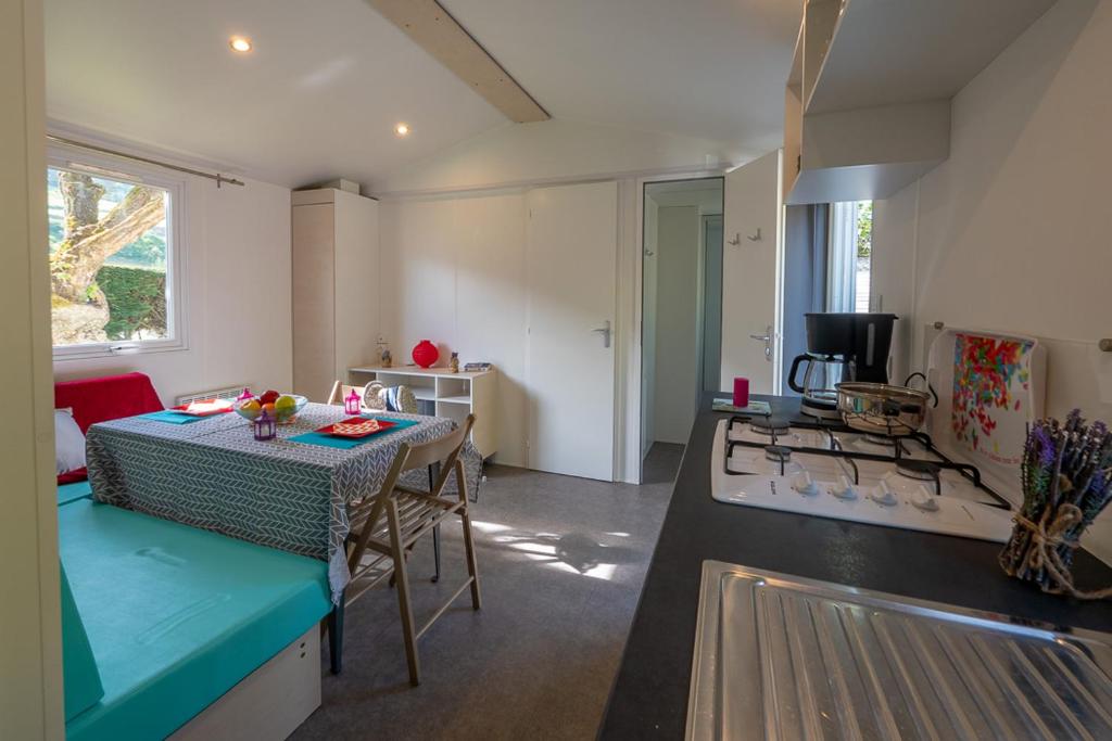 une cuisine avec une table et une cuisine avec une cuisinière dans l'établissement Camping Au Tour de l'Aveyron, à LʼHospitalet-du-Larzac