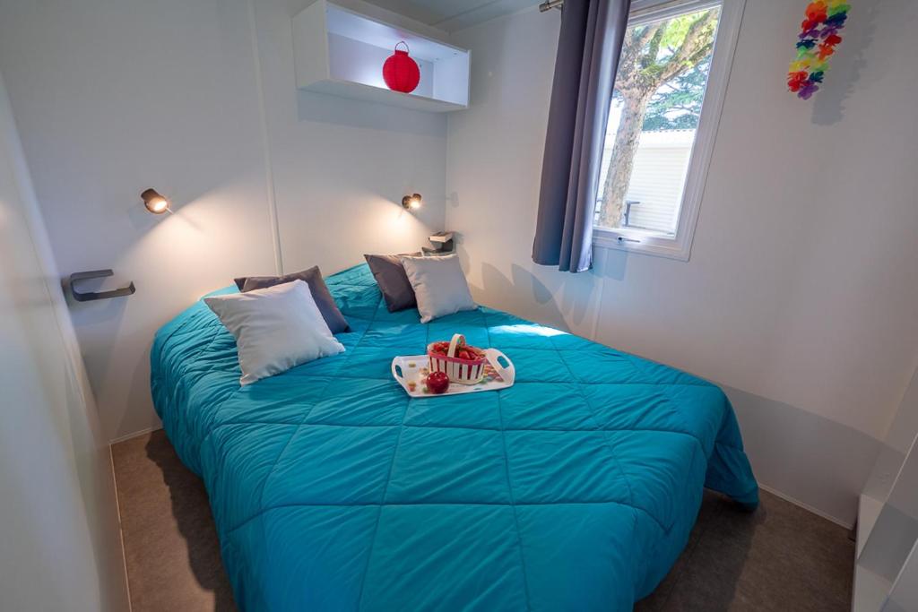 - une chambre avec un lit bleu et un plateau dans l'établissement Camping Au Tour de l'Aveyron, à LʼHospitalet-du-Larzac