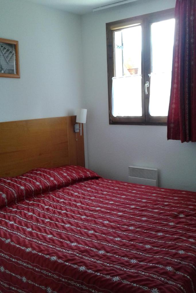 une chambre avec un lit avec une couverture rouge et une fenêtre dans l'établissement Vos vacances à Albiez Montrond, à Albiez-Montrond