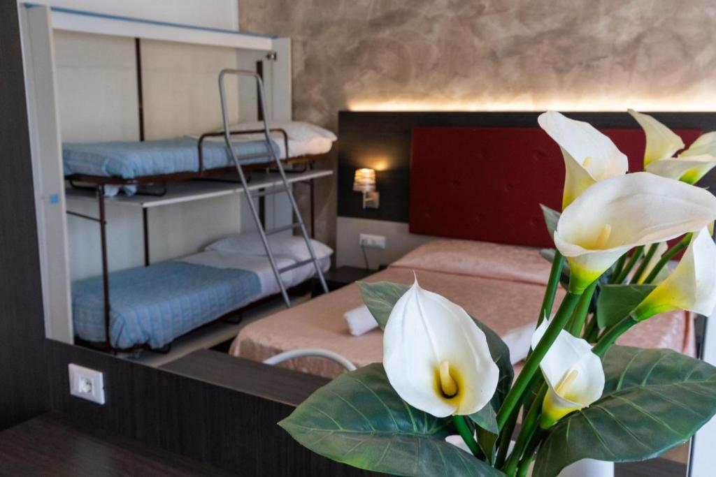 Cette chambre comprend 3 lits superposés et un vase fleuri. dans l'établissement Hotel Verdi, à Lido di Jesolo