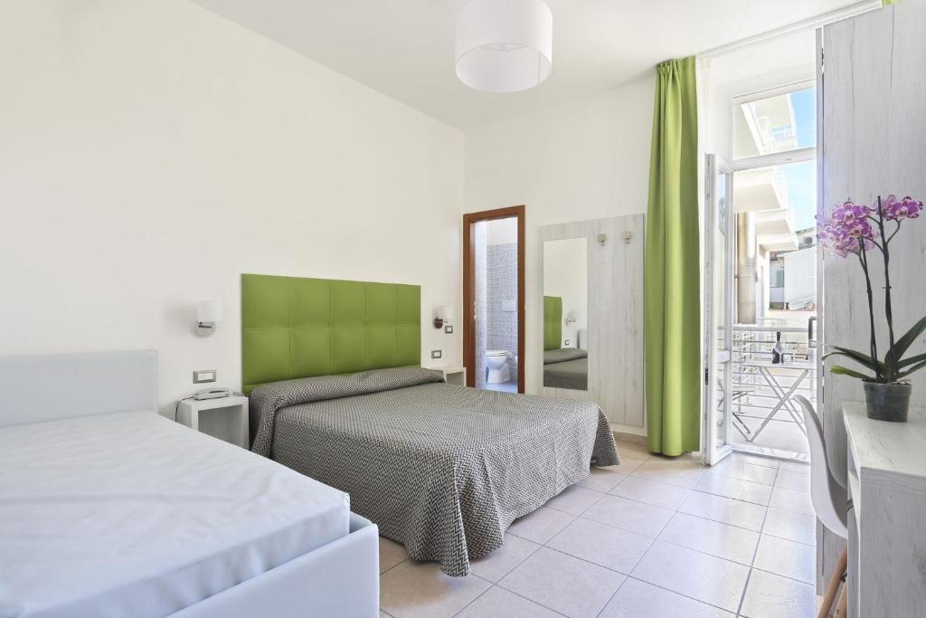 une chambre avec deux lits et une tête de lit verte dans l'établissement Hotel Nuovo Tirreno, à Lido di Camaiore
