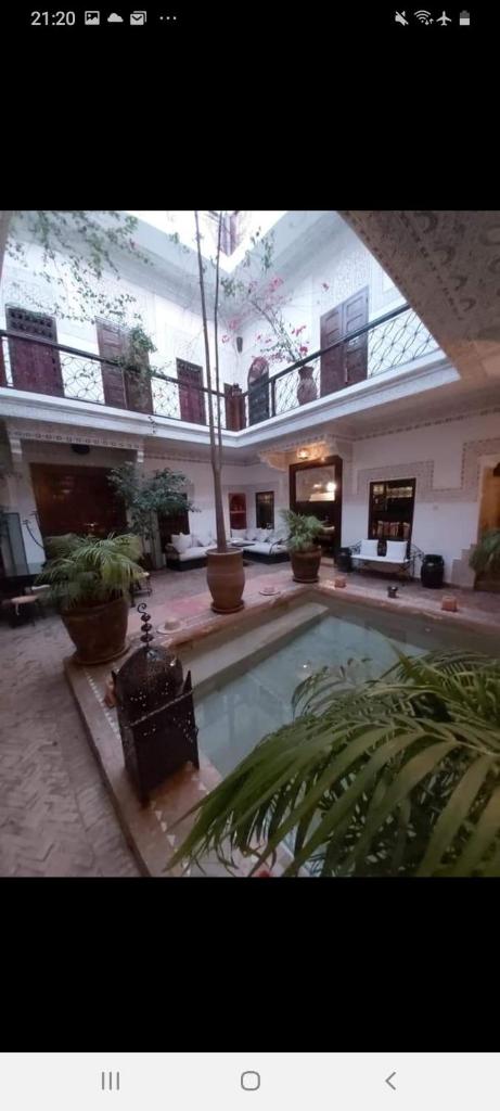 une grande cour avec une piscine dans un bâtiment dans l'établissement Riad Les Nuits de Marrakech, à Marrakech