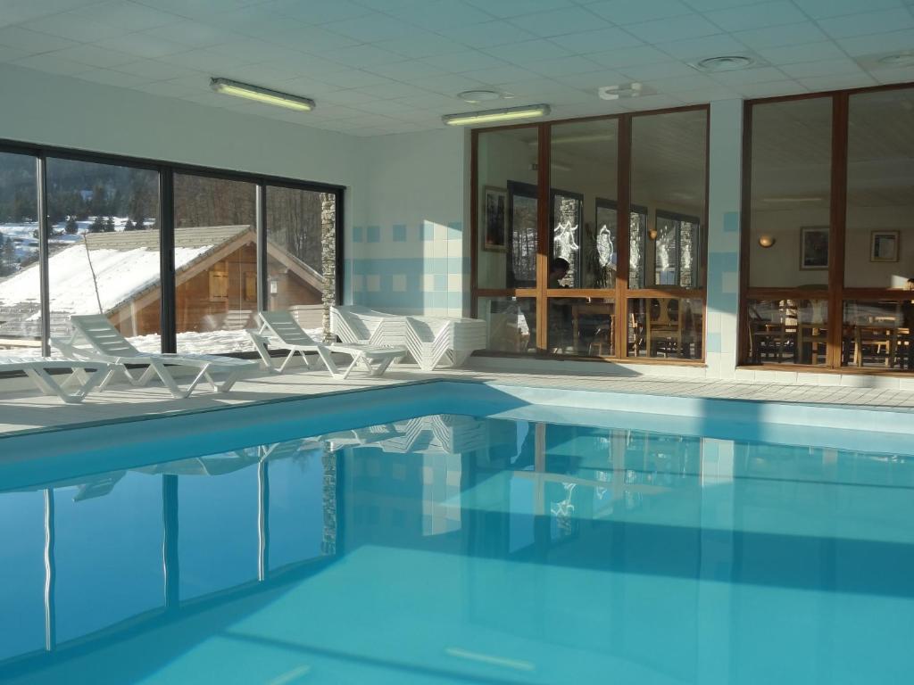 une piscine avec des chaises dans un immeuble dans l'établissement Residence Le Hameau du Puy by Actisource, à Saint-Étienne-en-Dévoluy
