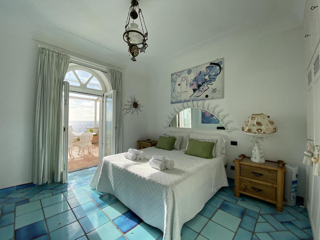 une chambre avec un lit et une grande fenêtre dans l'établissement Villa Teste di Moro, à Capri