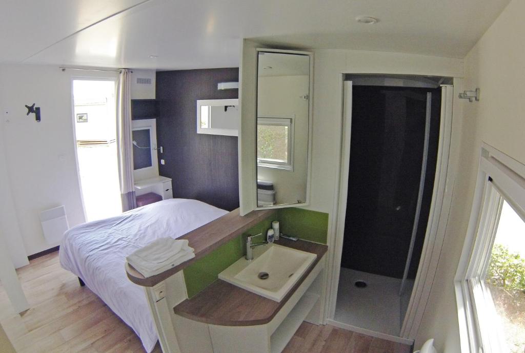 une chambre avec un lit, un lavabo et un miroir dans l'établissement Camping Domaine du Lac Chambon, à Murol