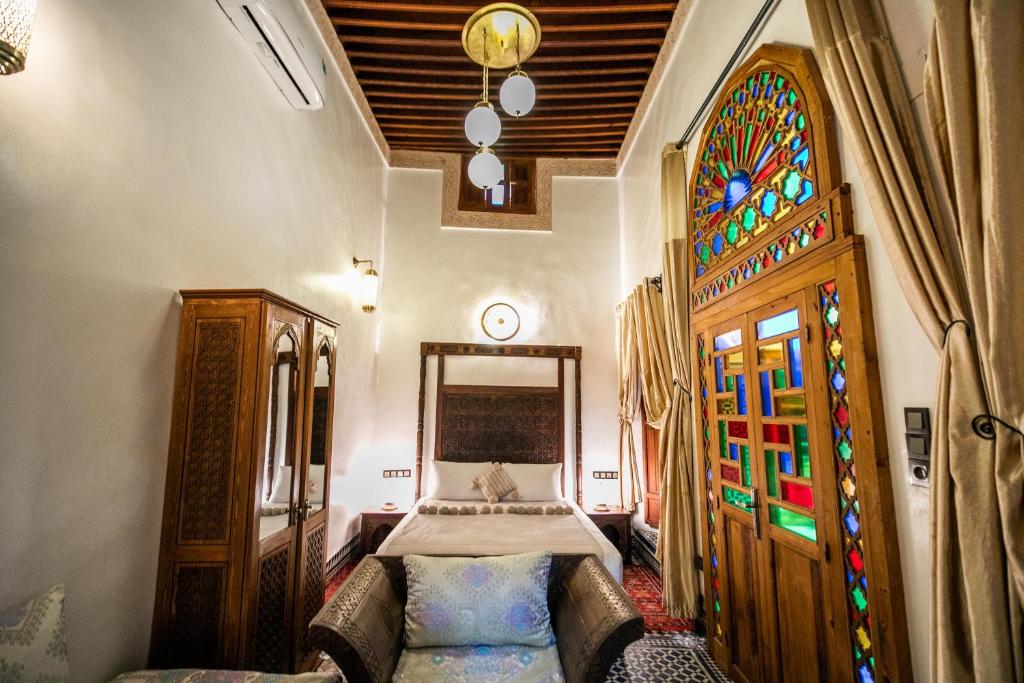 une chambre avec un lit et un vitrail dans l'établissement Dar Borj, à Fès
