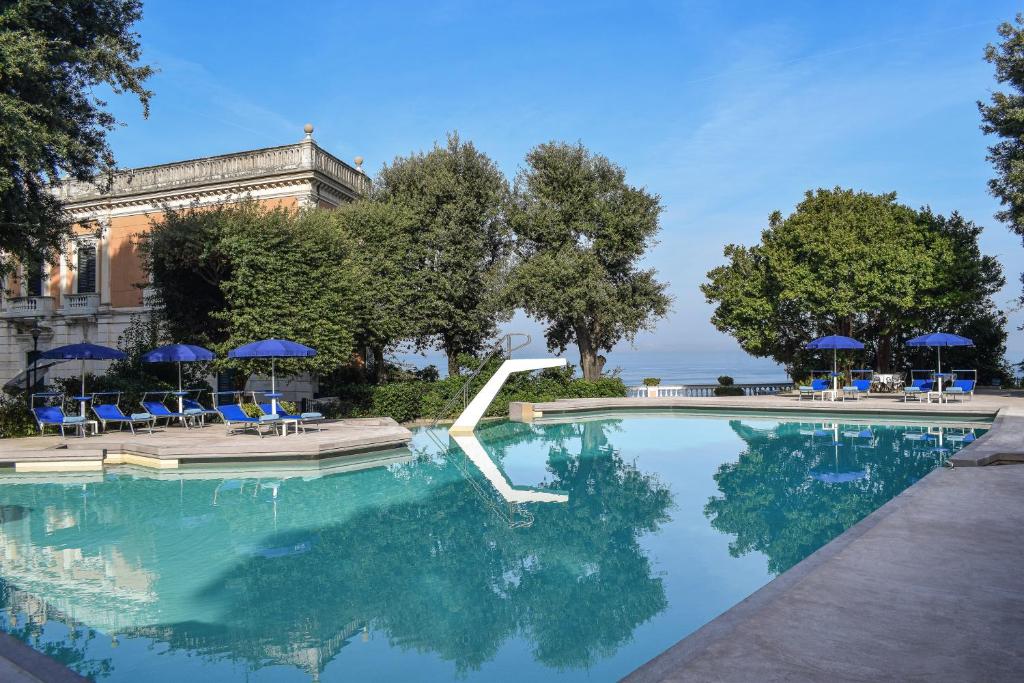 une piscine avec des chaises bleues et des parasols dans l'établissement Parco dei Principi, à Sorrente