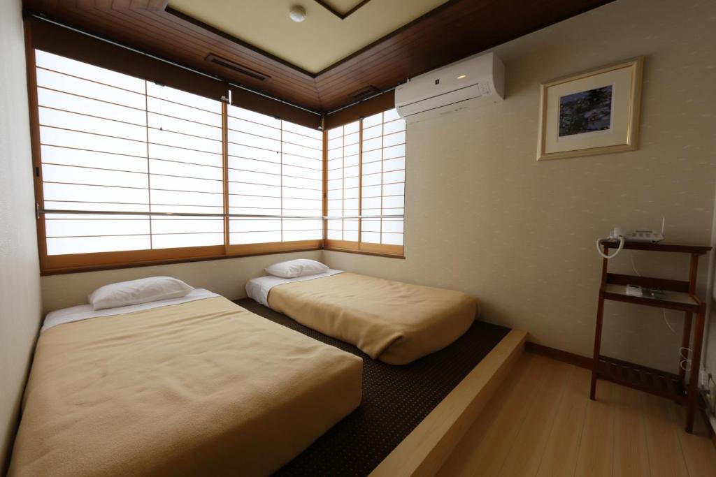 deux lits dans une chambre avec deux fenêtres dans l'établissement Tazuru, à Kyoto