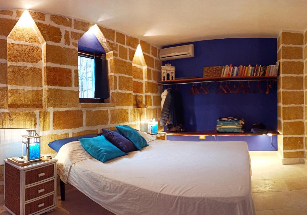 une chambre avec un lit dans un mur de pierre dans l'établissement VILLE GIRASOLI "VILLA NELLA BAIA" with PRIVATE SWIMMING POOL, à Tricase