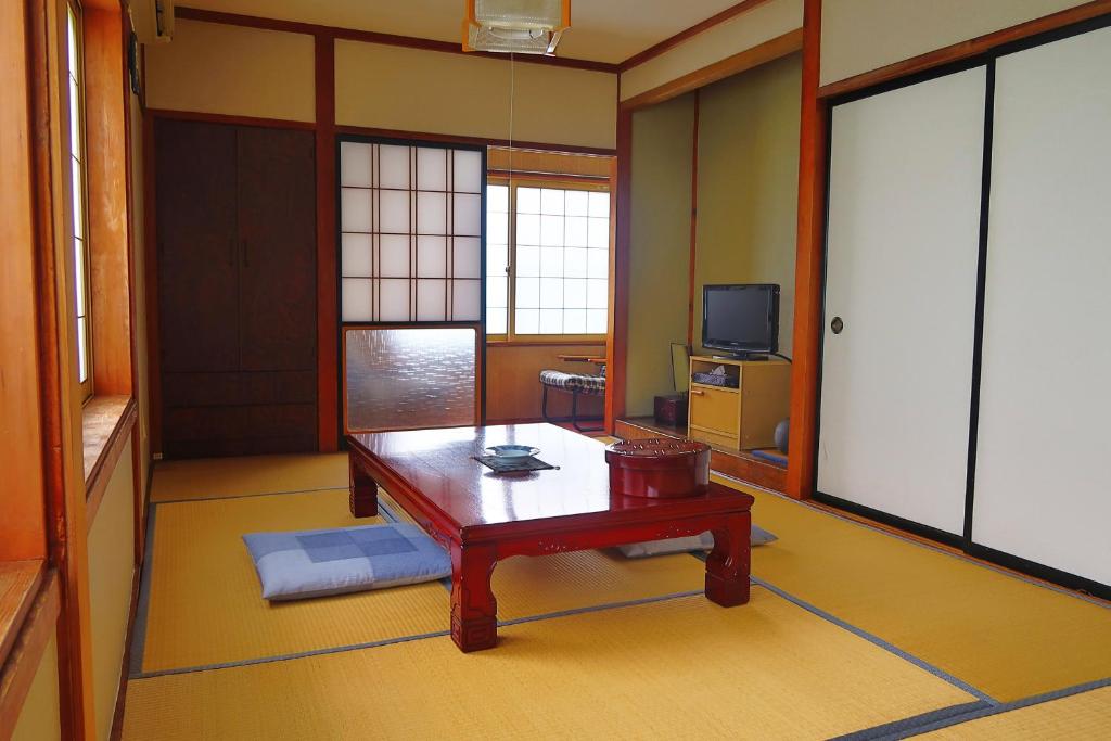 un salon avec une table et une télévision dans l'établissement 旅館FURUYA, à Hakuba