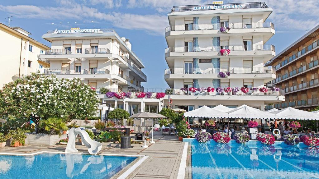 un hôtel avec une piscine devant un bâtiment dans l'établissement Hotel Sirenetta, à Lido di Jesolo