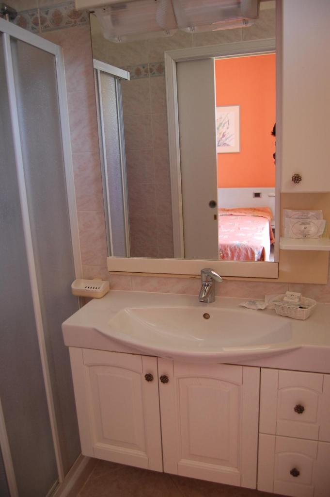 une salle de bain avec un lavabo blanc et un miroir dans l'établissement Hotel Villa Ombrosa, à Portoferraio