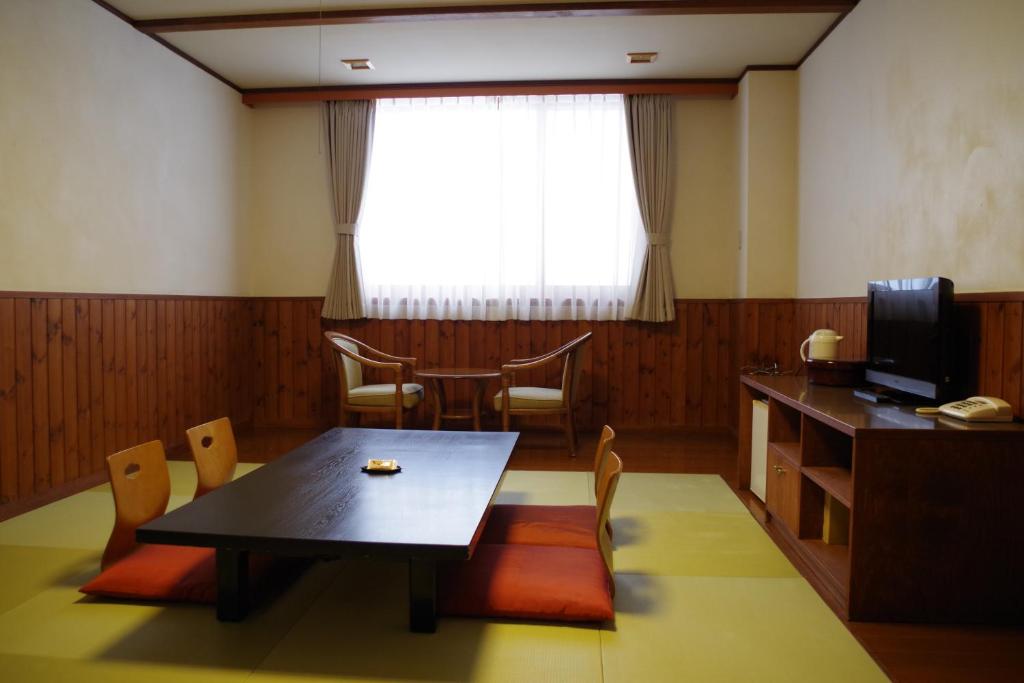 une salle à manger avec une table et des chaises et une fenêtre dans l'établissement Tomuraushionsen Higashi Taisetsuso, à Shintoku