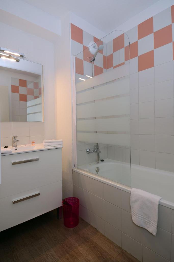 une salle de bain avec une baignoire, un lavabo et un miroir dans l'établissement Vacancéole - Les Chalets de l'Isard, aux Angles