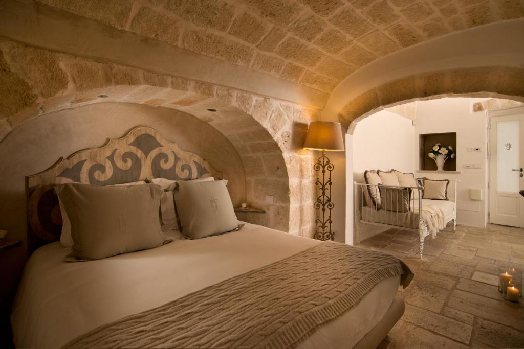 une chambre avec un grand lit avec un mur en pierre dans l'établissement Hotel Don Ferrante, à Monopoli
