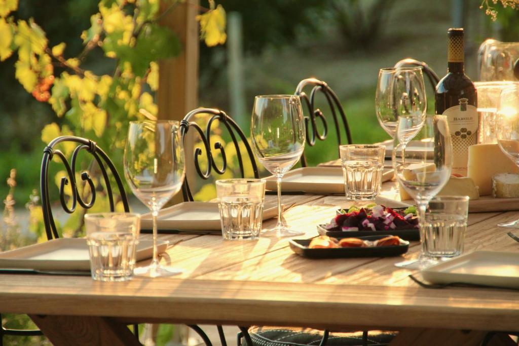 - une table en bois avec des verres à vin et de la nourriture dans l'établissement Villa La Mura - Luxury Pool by the Vineyard, à Costigliole dʼAsti