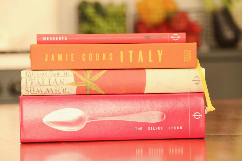 une pile de livres assises sur une table avec une cuillère dans l'établissement Villa La Mura - Luxury Pool by the Vineyard, à Costigliole dʼAsti
