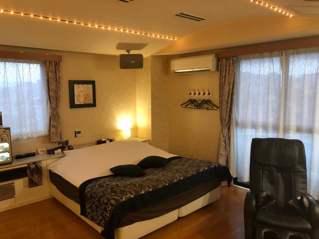 une chambre avec un lit et une chaise dedans dans l'établissement Restay Penthouse (Adult Only), à Kitakyūshū