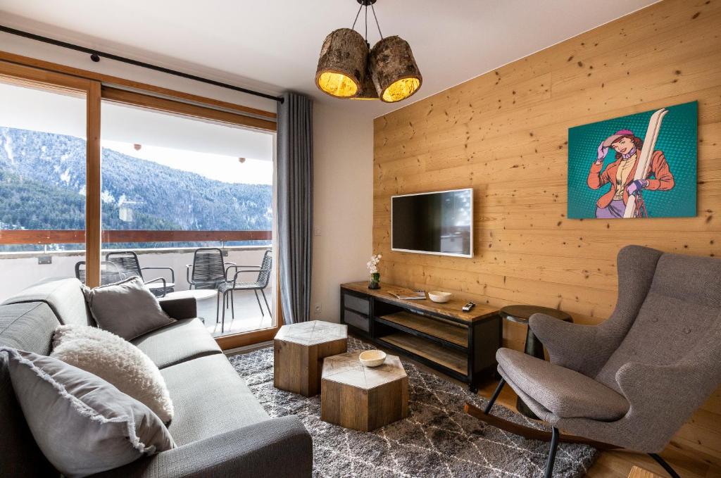 un salon avec un canapé, des chaises et une télévision dans l'établissement TERRESENS - Le Saphir, à Vaujany