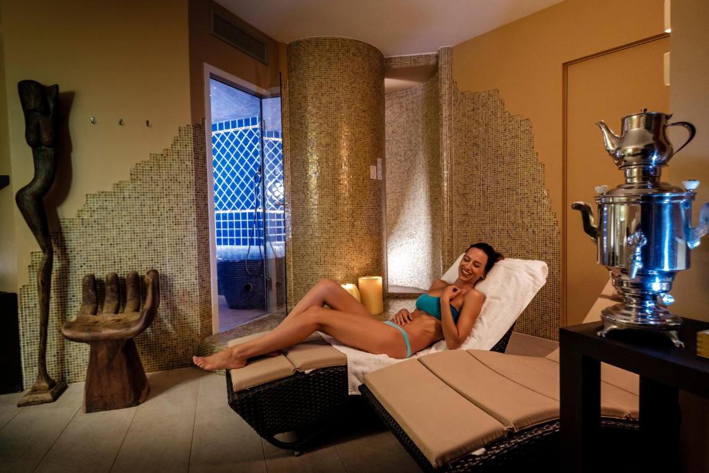 une femme assise sur une chaise dans une pièce dans l'établissement Pinetina Mare Baby Family Hotel, à Cervia