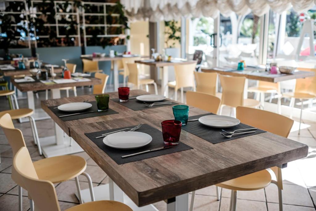 - une table en bois avec des assiettes et des serviettes dans un restaurant dans l'établissement Pinetina Mare Baby Family Hotel, à Cervia 106 autres photos