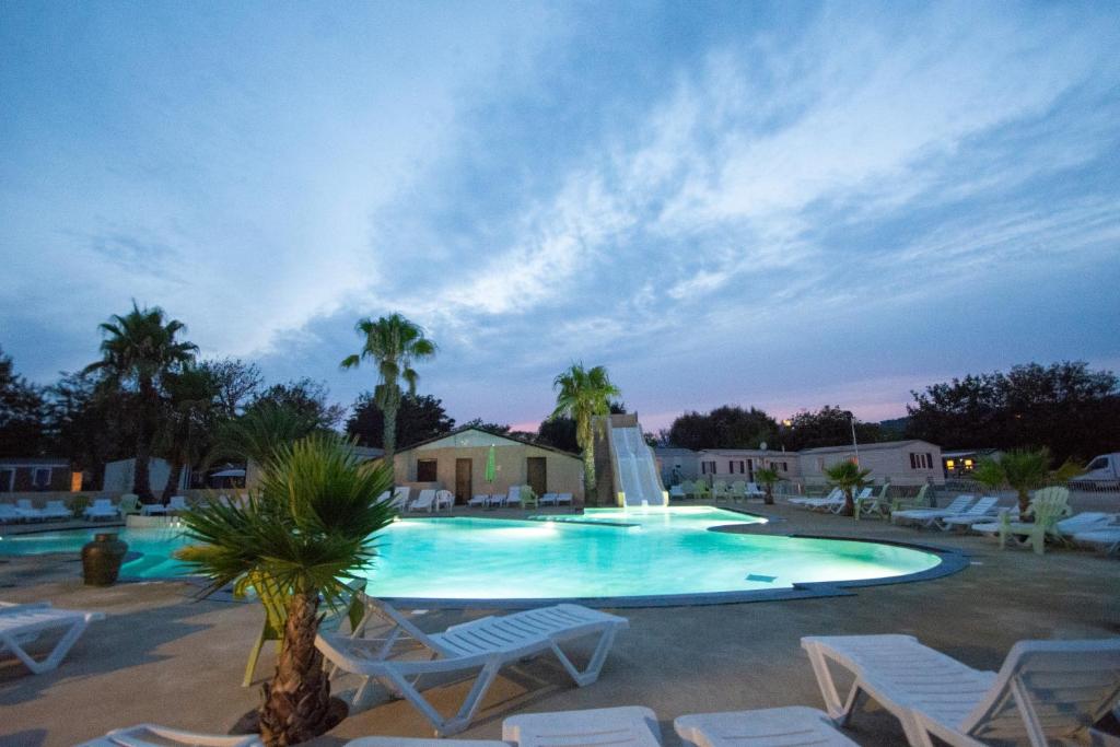 une grande piscine avec des chaises et une fontaine dans l'établissement Camping Domaine Du Golfe De Saint Tropez, à Grimaud