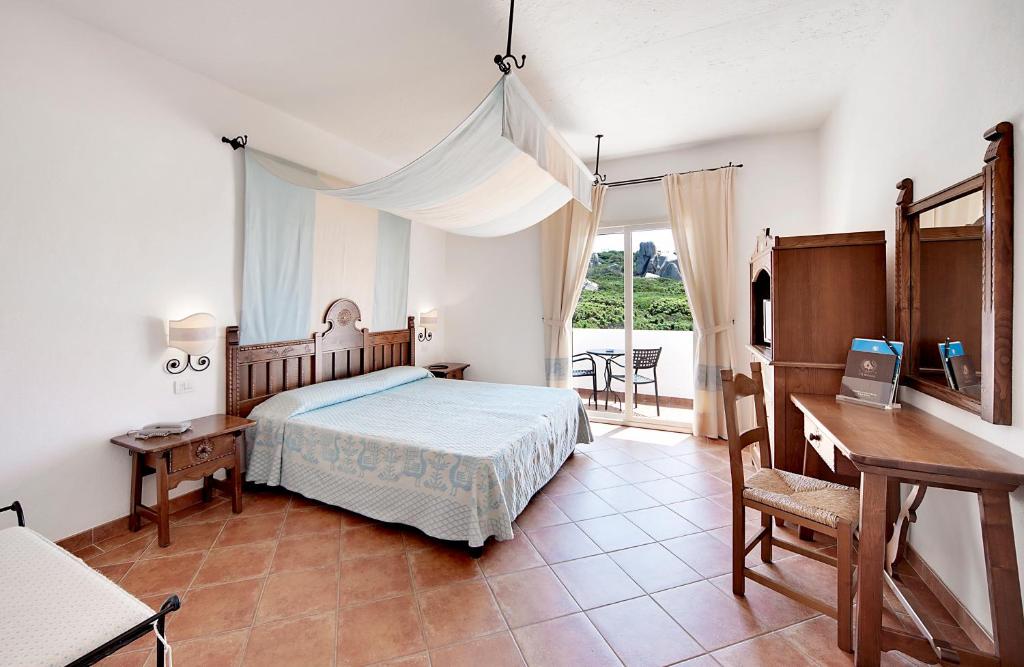 une chambre avec un lit, un bureau et une fenêtre dans l'établissement COLONNA GRAND HOTEL CAPO TESTA, a Colonna Luxury Beach Hotel, Santa Teresa Sardegna, à Santa Teresa Gallura 52 autres photos