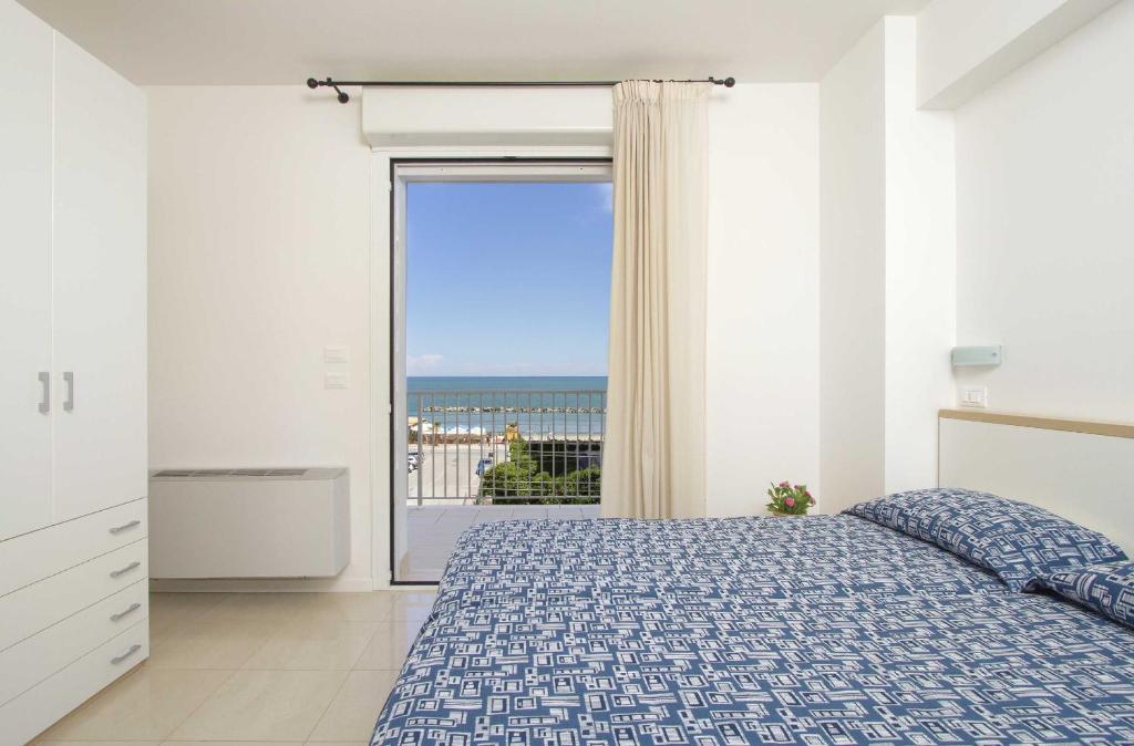 une chambre avec un lit et une grande fenêtre dans l'établissement Residence I Delfini, à Cupra Marittima