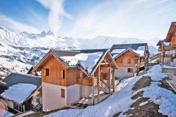un groupe de maisons au sommet d'une montagne enneigée dans l'établissement Vos vacances à Albiez Montrond, à Albiez-Montrond