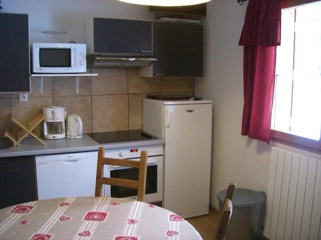 Il comprend une petite cuisine avec une table et un réfrigérateur blanc. dans l'établissement Appartement Claparelle - Les 2 Alpes, à Les Deux Alpes