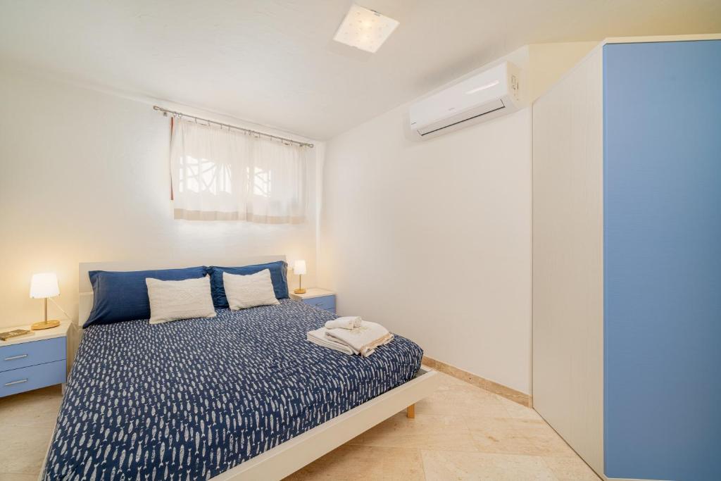 une chambre avec un lit bleu et une fenêtre dans l'établissement Villa Adele, con piscina a 700 mt dal mare, à Monte Petrosu