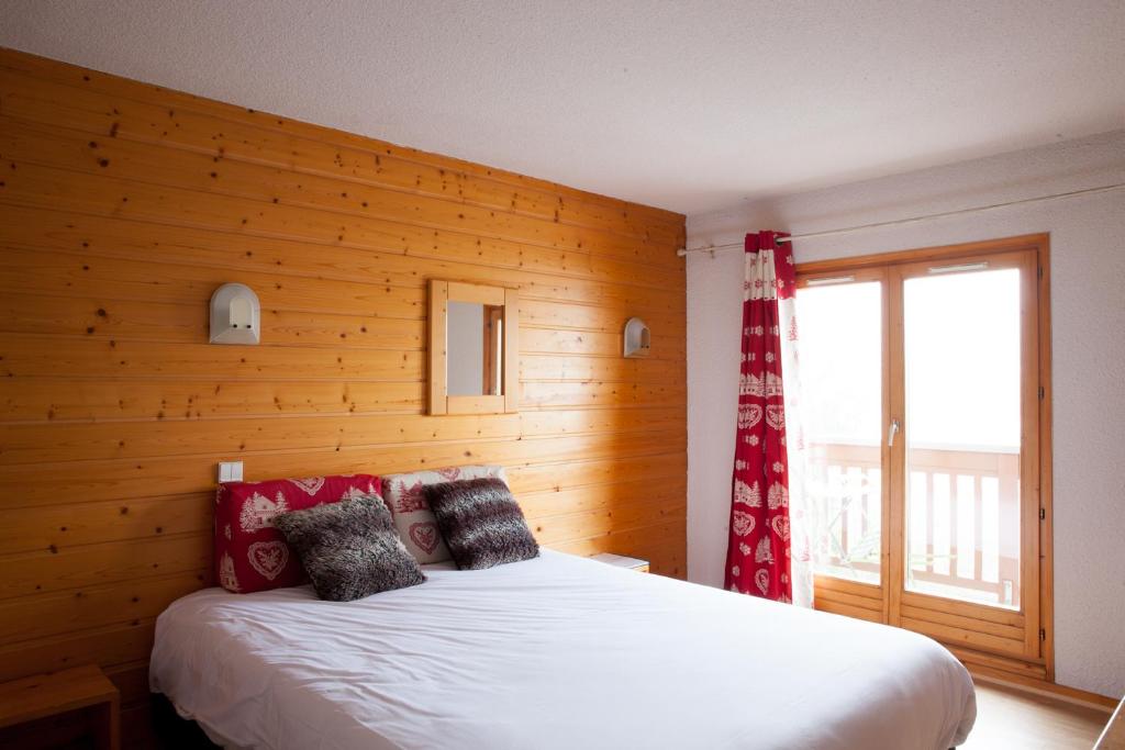 - une chambre avec un lit et un mur en bois dans l'établissement Le Floralp, à Combloux