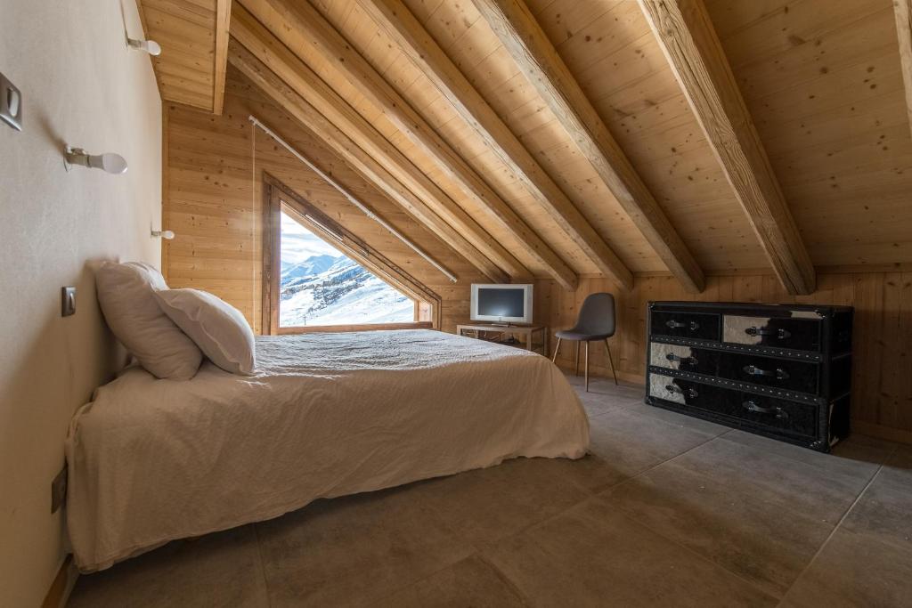 une chambre avec un grand lit et une fenêtre dans l'établissement ODYSSEE B301 Duplex mansarde sur les pistes, vue panoramique, à La Toussuire