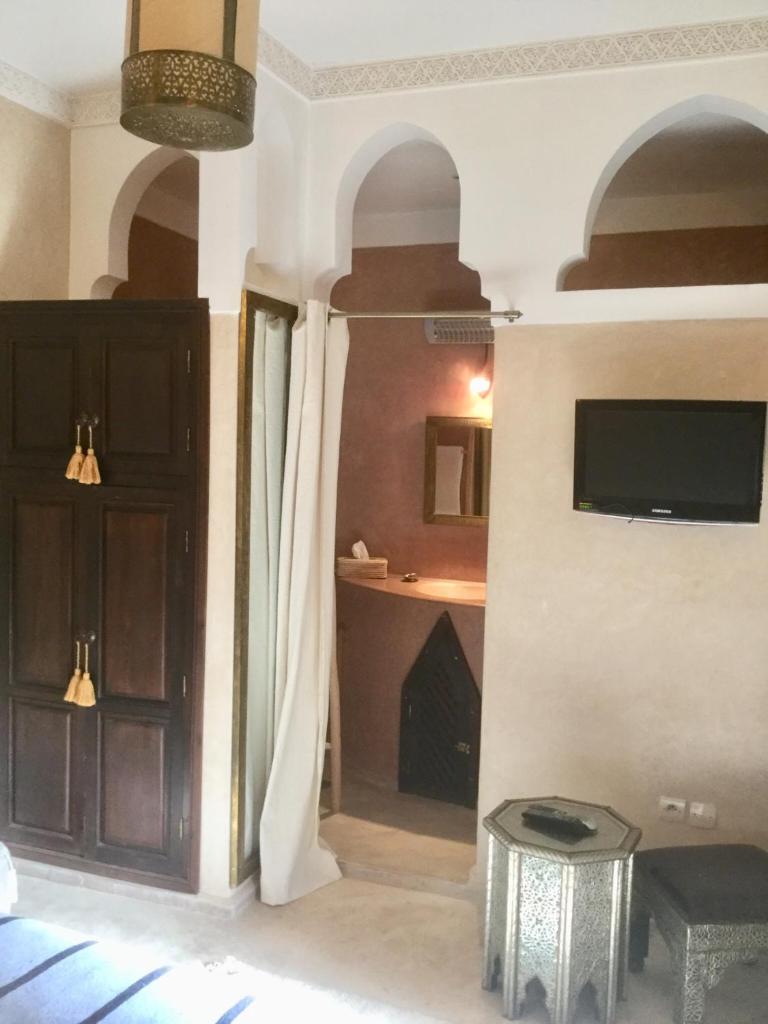 Cette chambre dispose d'une porte, d'une télévision et d'une table. dans l'établissement riad mimoune, à Marrakech