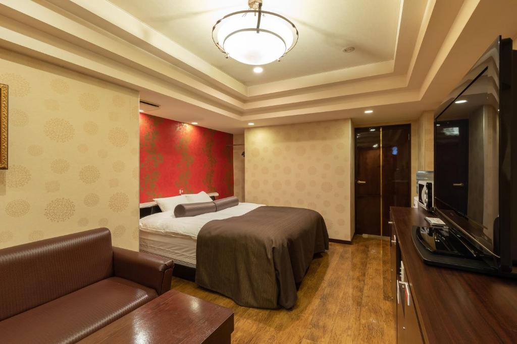une chambre avec un lit, un canapé et une télévision dans l'établissement ホテル アン 岐阜-大人専用, à Gifu