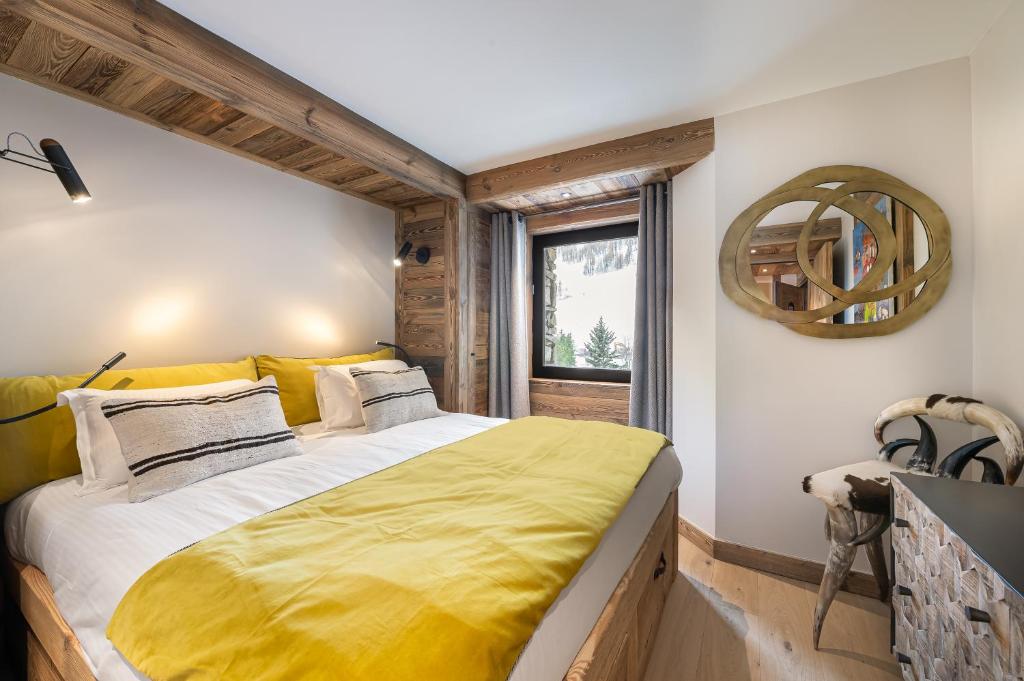 une chambre avec un grand lit avec une couverture jaune dans l'établissement Appartement Flocon - LES CHALETS COVAREL, à Val dʼIsère