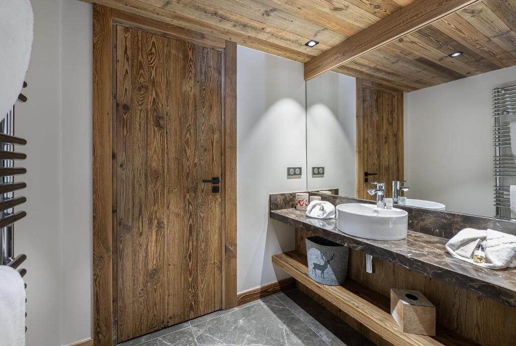 La salle de bains est pourvue d'un lavabo et d'une porte en bois. dans l'établissement Appartement Etoile - LES CHALETS COVAREL, à Val dʼIsère