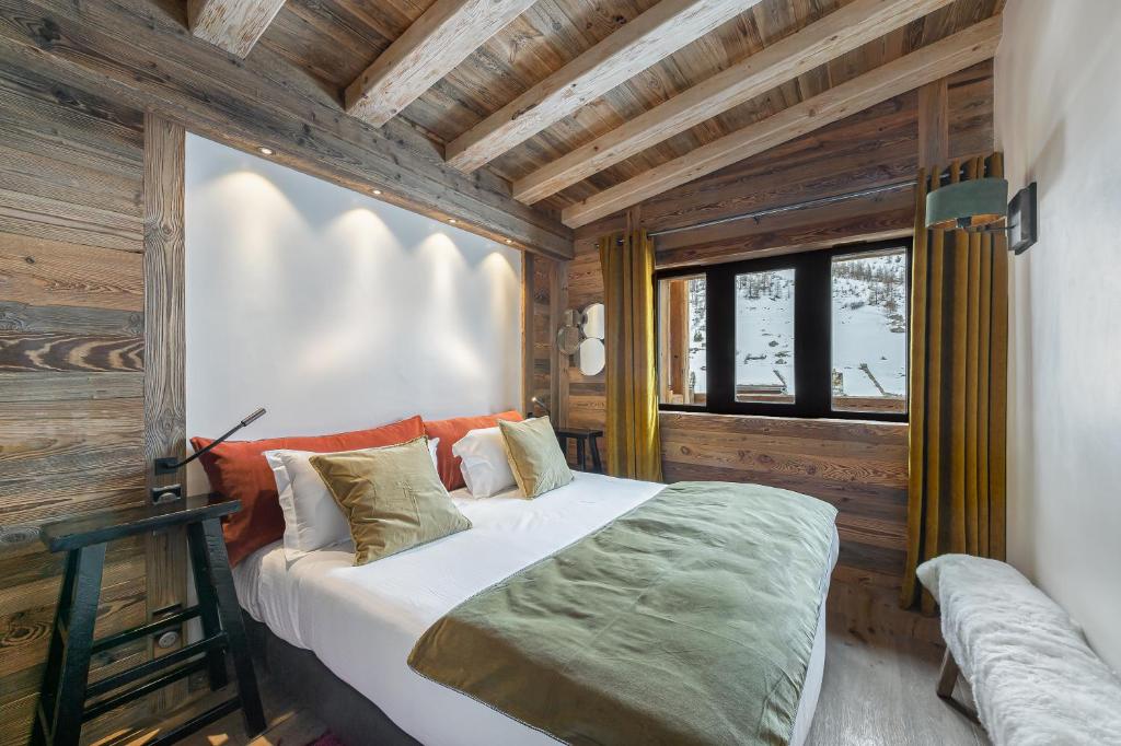une chambre avec un lit dans une pièce aux murs en bois dans l'établissement Penthouse Flèche - LES CHALETS COVAREL, à Val dʼIsère