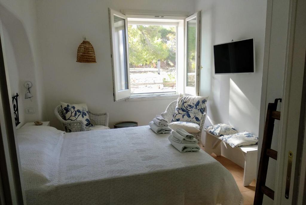 une chambre blanche avec un lit et une fenêtre dans l'établissement Trullammare, à Monopoli 95 autres photos