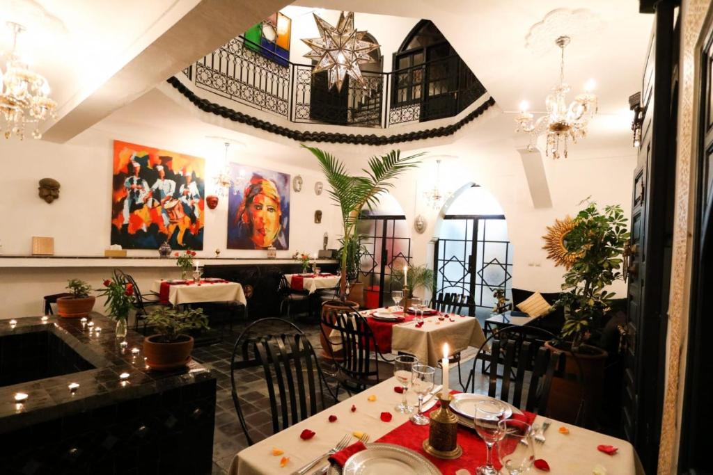 un restaurant avec des tables, des chaises et des peintures murales dans l'établissement La Voûte Étoilée, à Marrakech